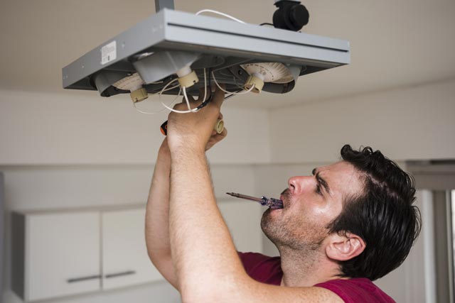 electricien laval homme repare un plafonnier a lumiere focale maison